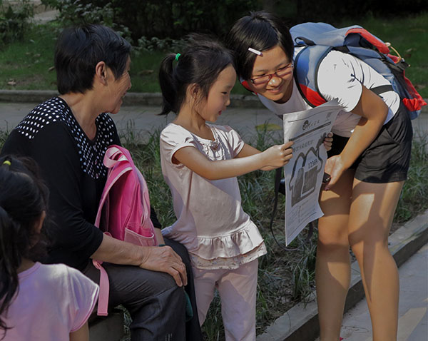 "Ivy" hands out the papers and the Huixing Journal attracts the attention of a young reader. (Jock Lauterer photo)