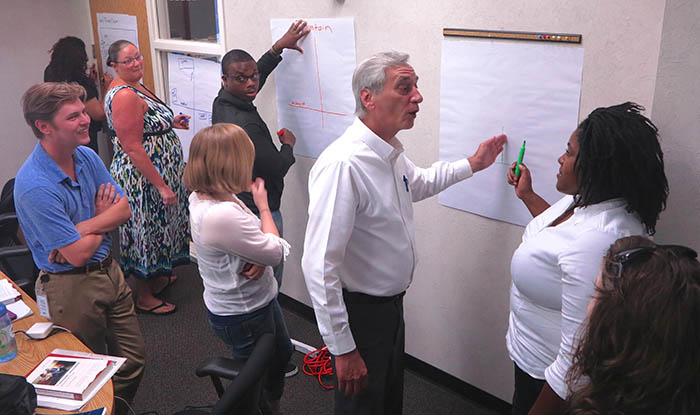 During an interactive part of the Roadshow Workshop at the Greenville Daily Reflector, veteran reporter Michael Abramowitz , center, instructs Cora Taft, right, on the finer points of Greenville goegraphy, other staffers from Cooke newspapers work on their "story-mapping" projects. (Jock Lauterer photo)