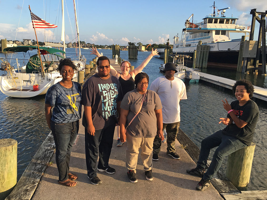 With sun setting and the lovely Ocracoke harbor for their backdrop, the PYO/Durham VOICE team strike a pose, left to right, Natasha Graham, Yusuf Shah, Gwen Payne, Chistian Lawrence, LaMon James and Bruce Wilkinson. (Jock Lauterer photo)