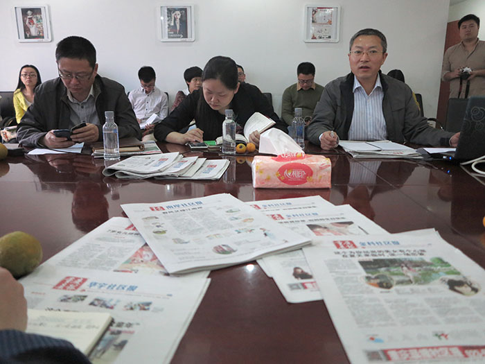 The new community papers are displayed at the staff meeting, run by Mr. Zhao, right.