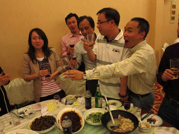 Pleased with how the workshop has gone, organizer and Shanghai community newspaper editor Zhou Chen, pointing, toasts his guests at a celebratory dinner. (Jock Lauterer photo)