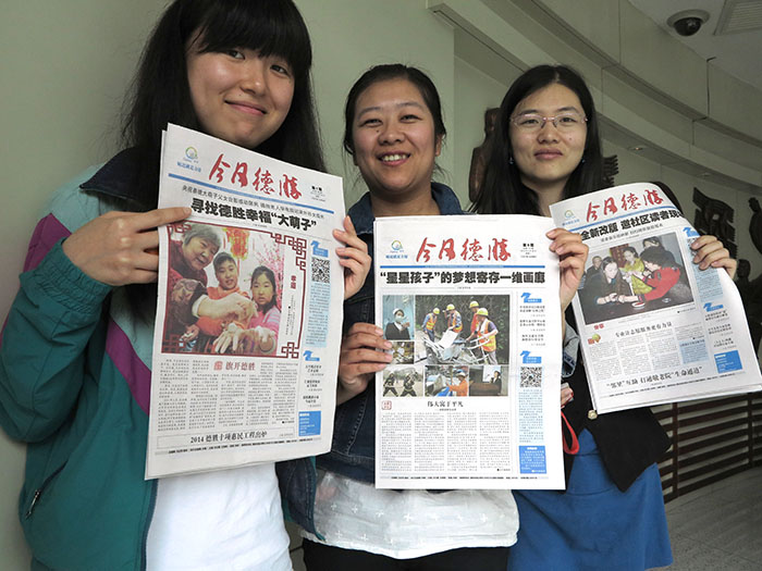 The staff of Desheng Today proudly hold up examples of their work. (Jock Lauterer photo)