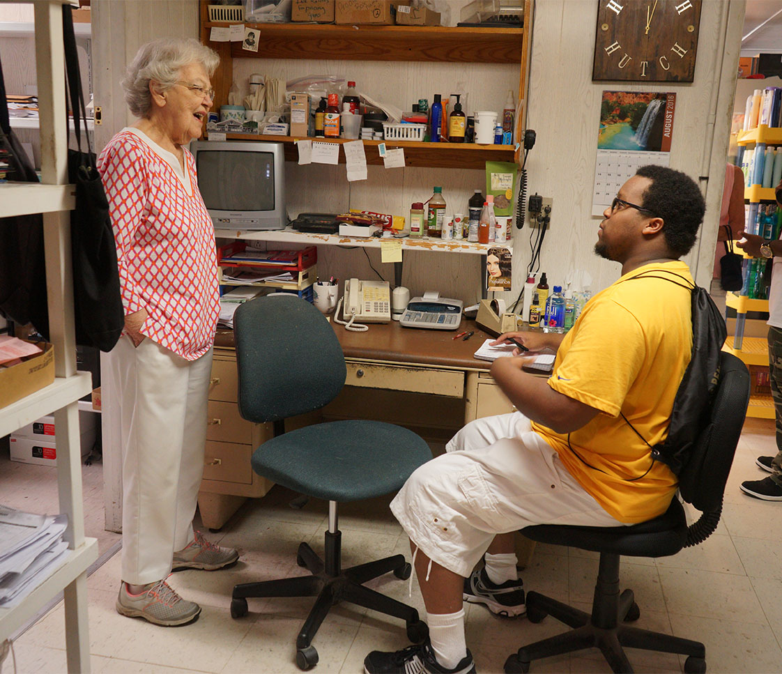 Getting an earful: VOICE reporter Yusuf Shah listens as 83-year-old Julie Hutcherson relates the long history of Ocracoke's iconic Variety Store. (Jock Lauterer photo)